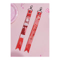 Front and back of the Saki Hanami ribbon keychain: illustration with signature, and the name Saki Hanami
