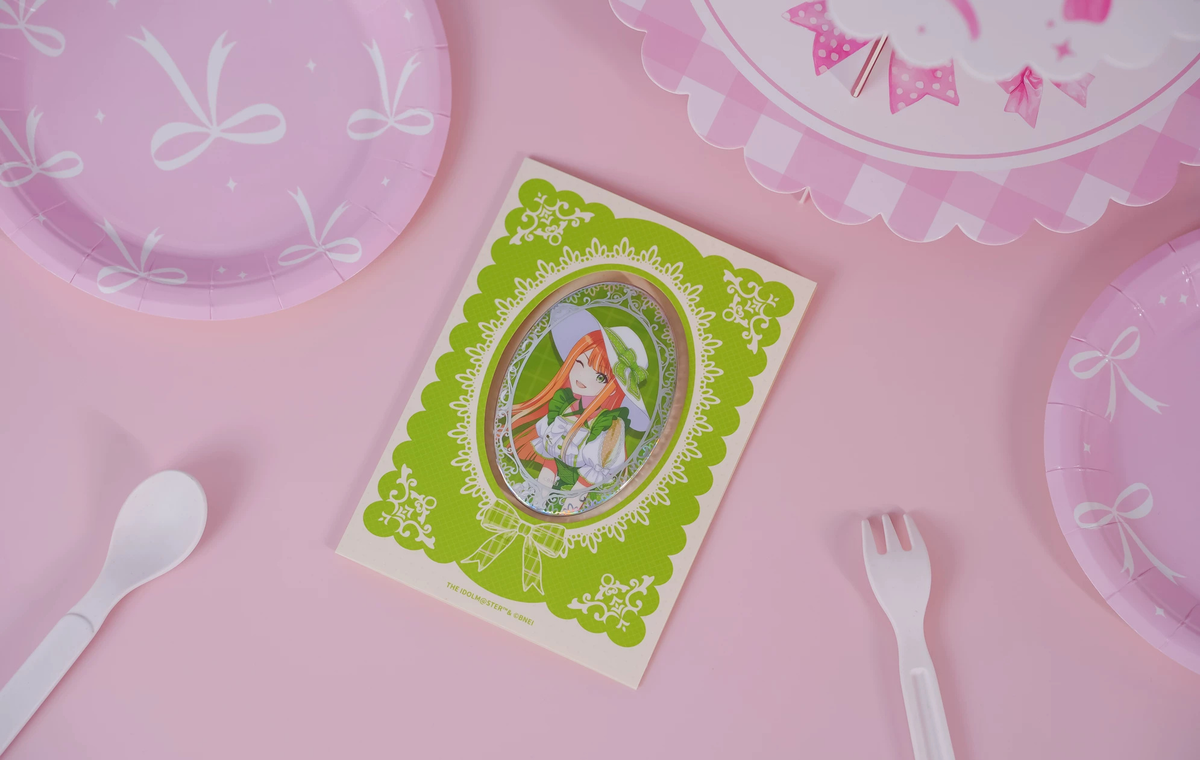 The Sumika Shiun badge on its backing card, photographed on a pink table with paper plate and cutlery props