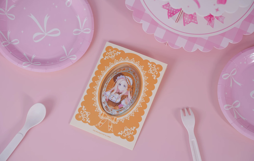 Sena Juo badge in its orange lace-patterned backing card on a pink table with tableware (props not included)