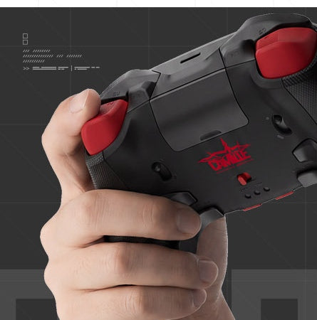 Hand holding the Camille Edition controller, showing the rear buttons and the red CAMILLE logo