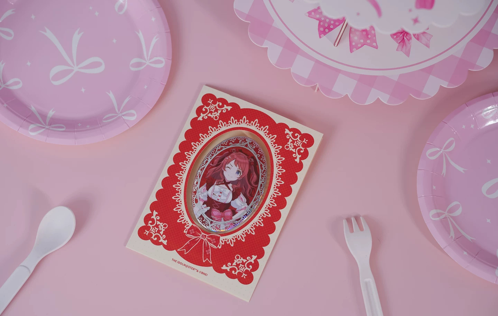 Saki Hanami badge in its red lace-patterned backing card on a pink table with tableware (props not included)