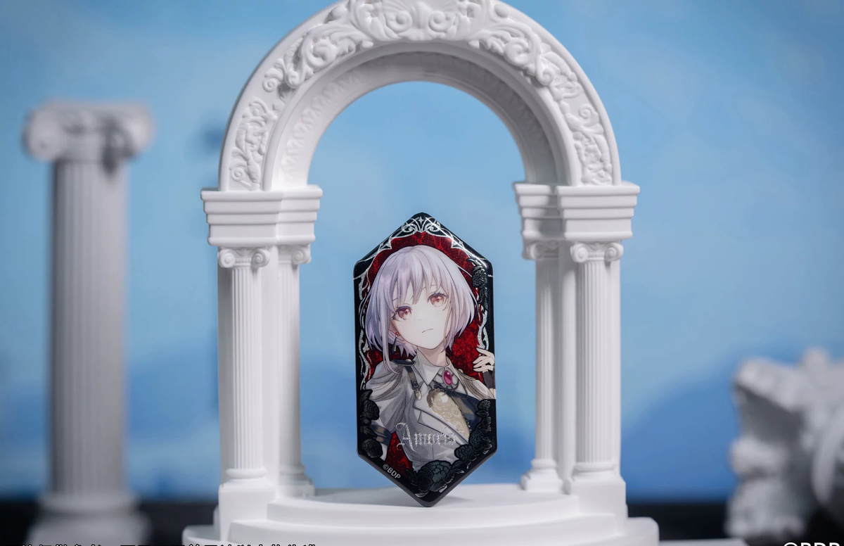Amoris (Nyamu Yutenji) badge standing in a white arch display prop