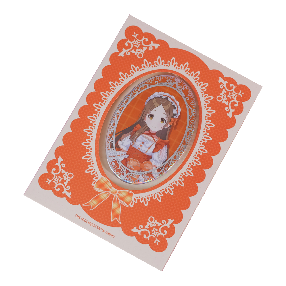 China Kuramoto oval holographic badge on its orange lace-patterned backing card.