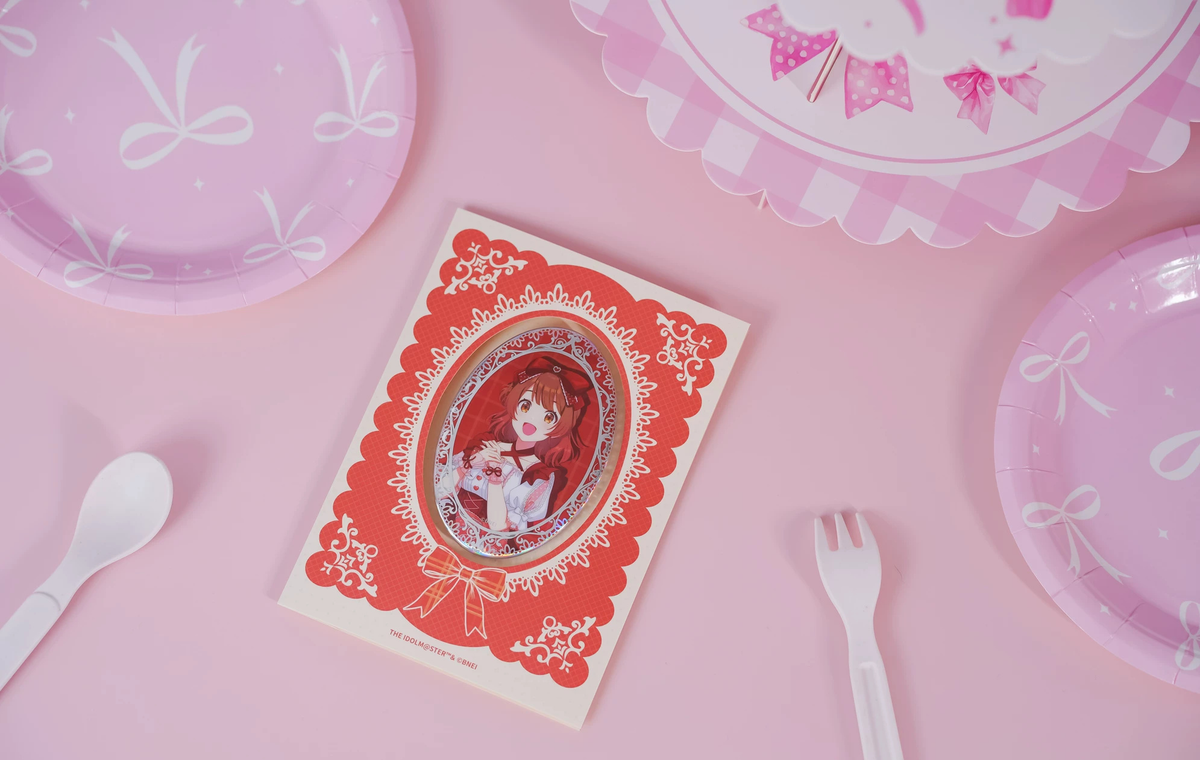 The Ume Hanami badge on its backing card, photographed on a pink table with paper plate and cutlery props
