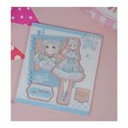 Acrylic stand parts on the printed sheet: Lilja Katsuragi figure in a pale blue lolita dress, base and signature plate