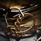 Gold-tone twisted knot linked to a silver-tone ring engraved 'The Hofmann Knot', with a brown leather cord