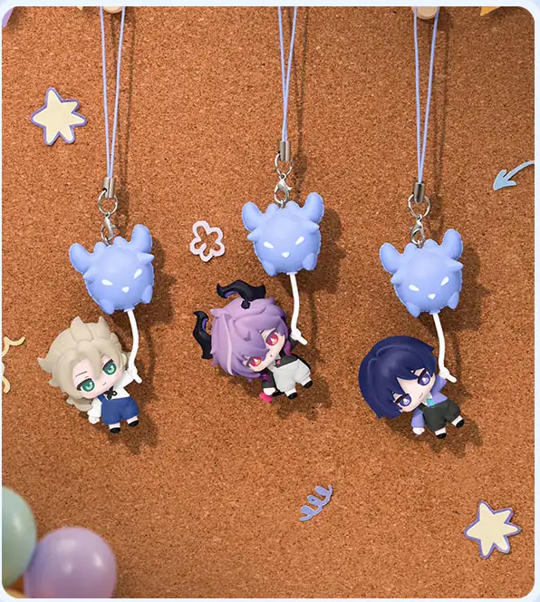 Three charms hanging from their cords on a corkboard