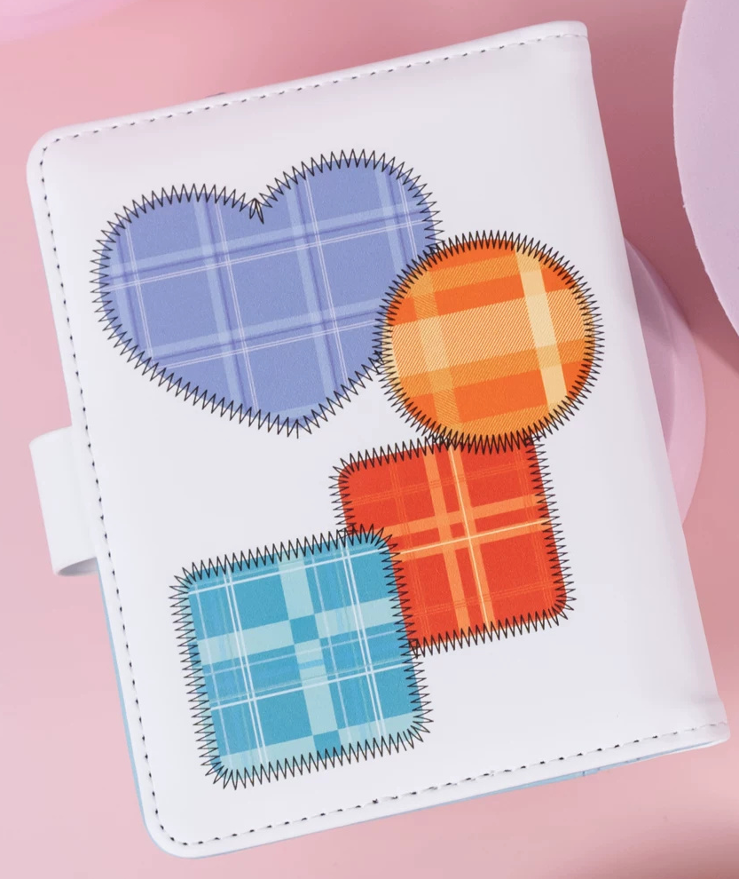 White cover of the Class 1-2 passport case with periwinkle, orange, red-orange and light-blue plaid patches